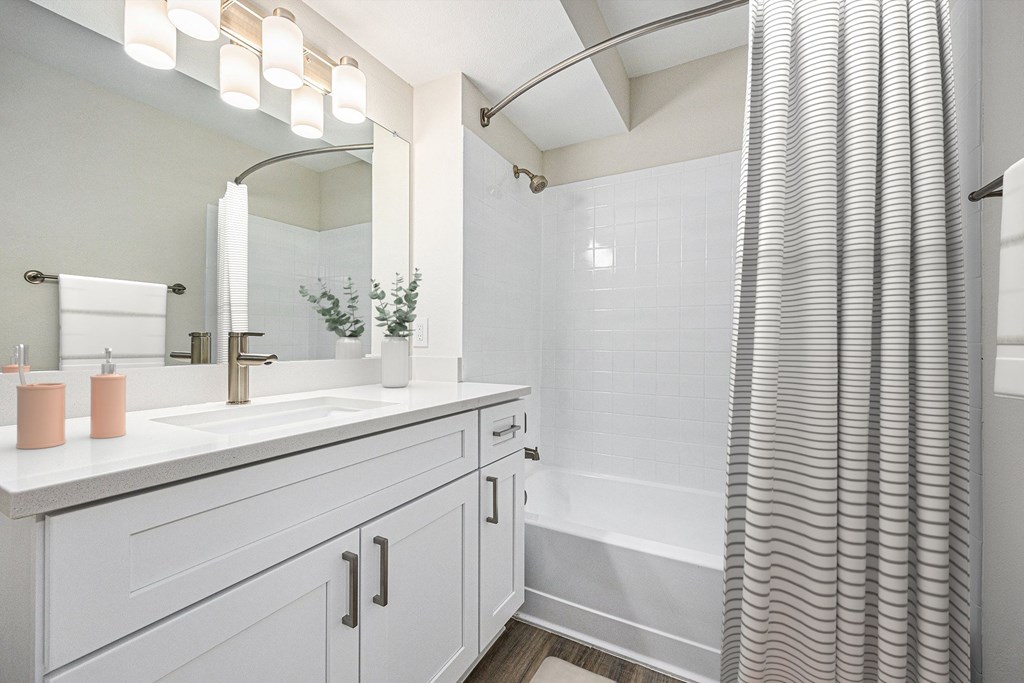 A bathroom with a white sink and a white shower curtain.