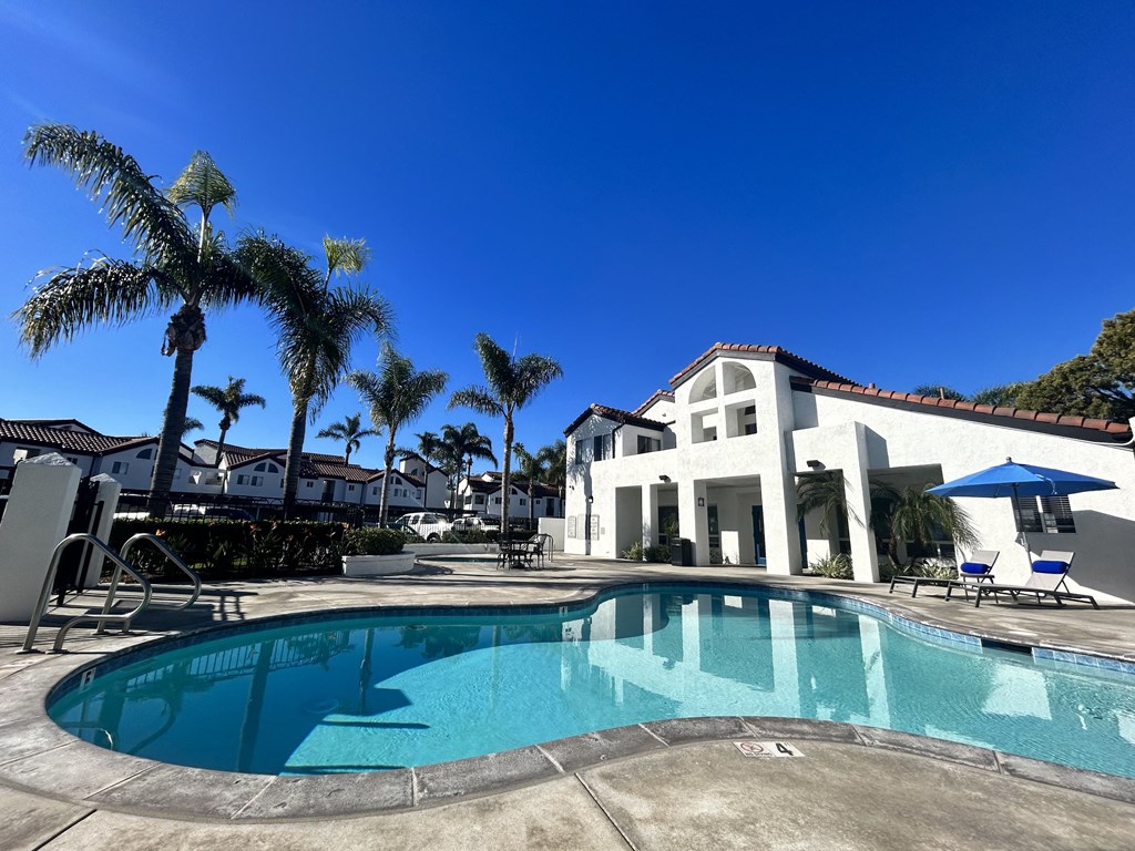 a swimming pool with palm trees in front of a Newport Palms Apartments