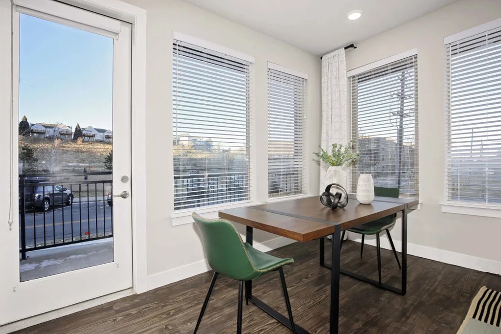 A room with a table and chairs and a view of a street outside.