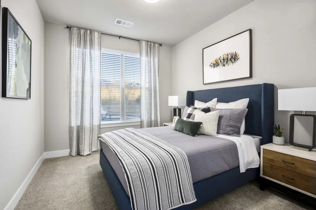 A bedroom with a large bed and a window with curtains.