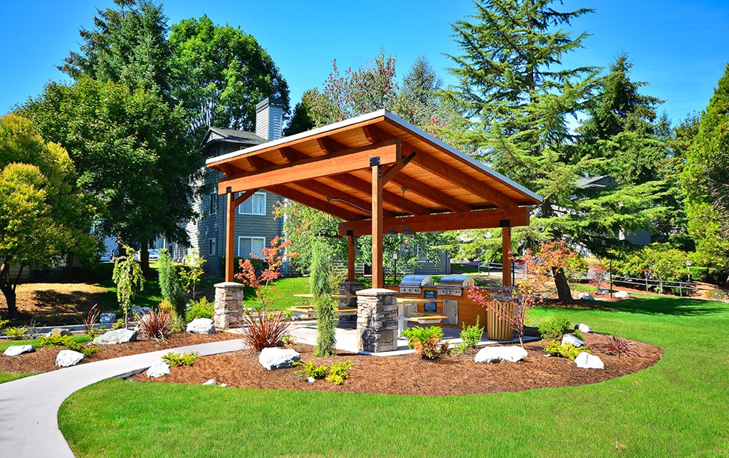 an outdoor kitchen with a wooden awning and stone pillars