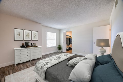 A bedroom with a bed, dresser, and a plant.