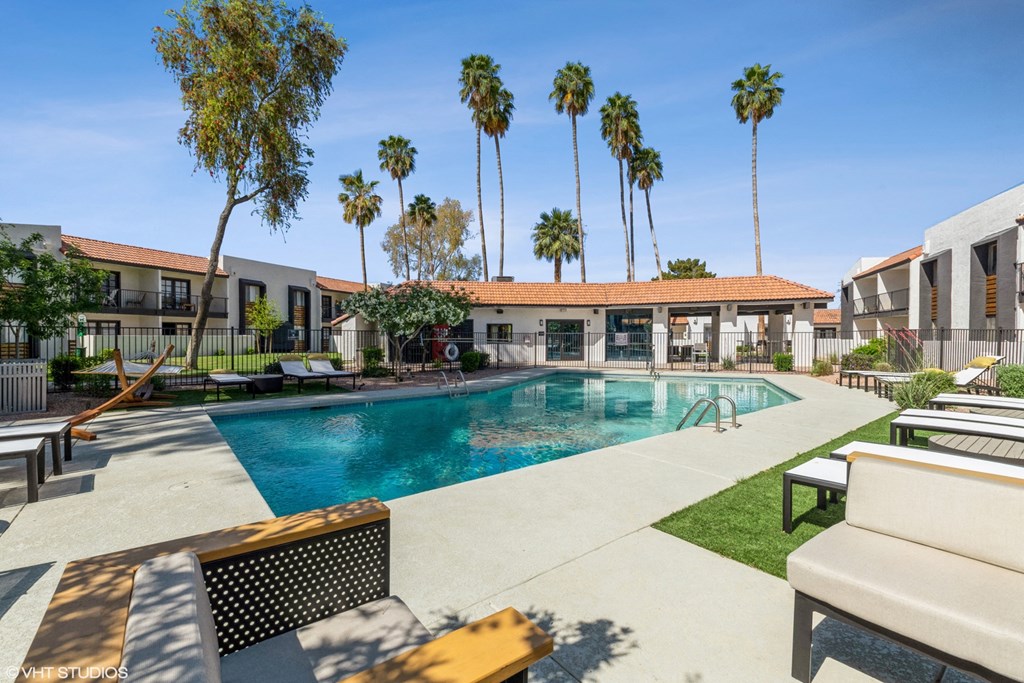 a swimming pool with lounge chairs and palm trees in the background