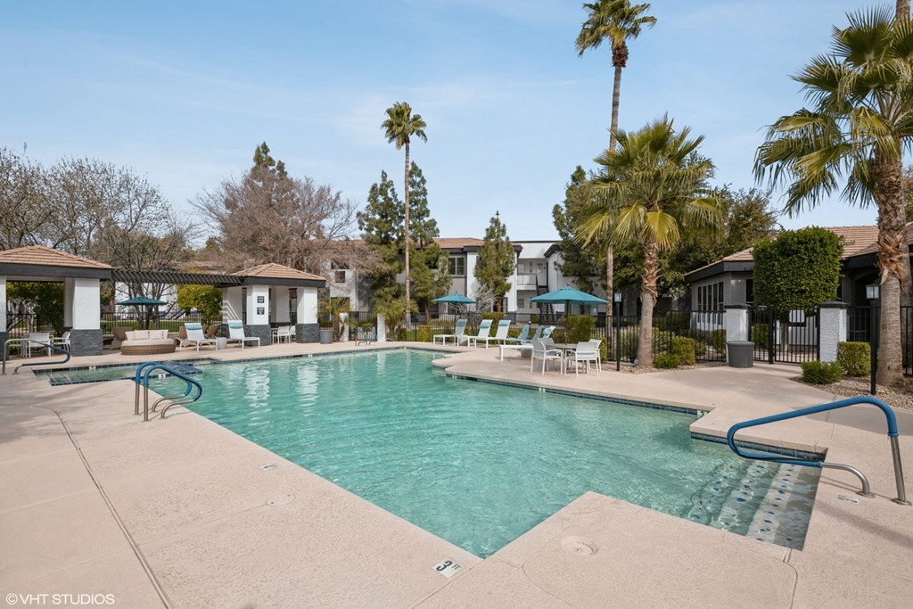 a swimming pool with palm trees and apartments in the background