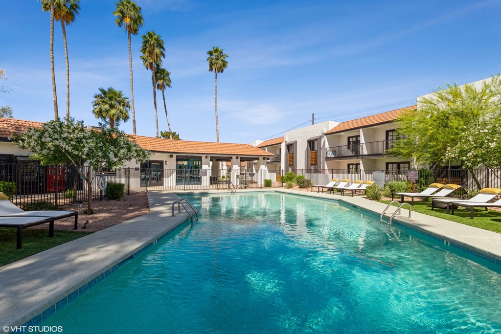 a swimming pool with lounge chairs and palm trees in the background