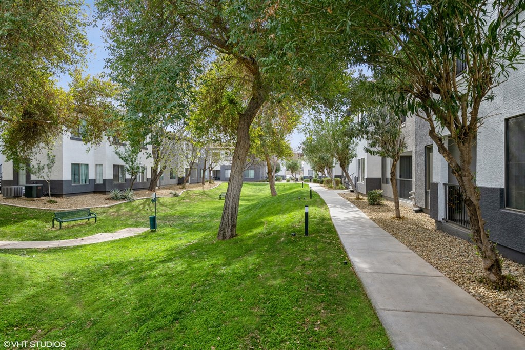 a park with green grass and trees in front of apartments