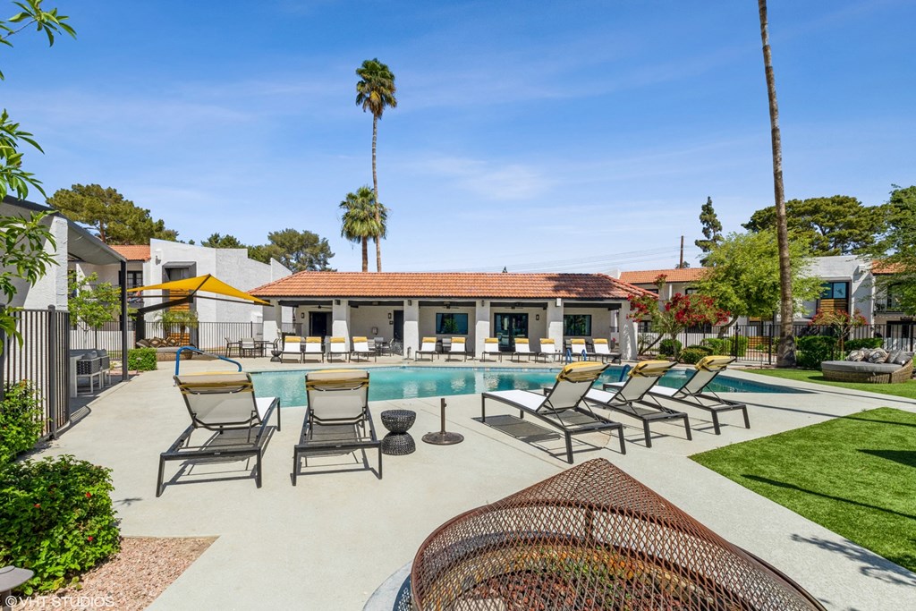 a swimming pool with chaise lounge chairs and a clubhouse in the background