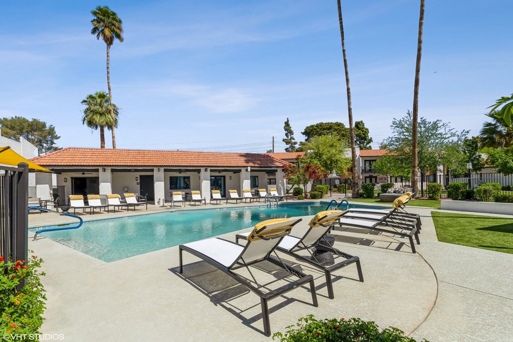 a swimming pool with chaise lounge chairs and a building in the background