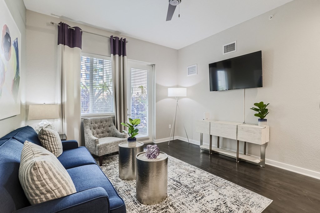 a living room with a blue couch and a tv on the wall