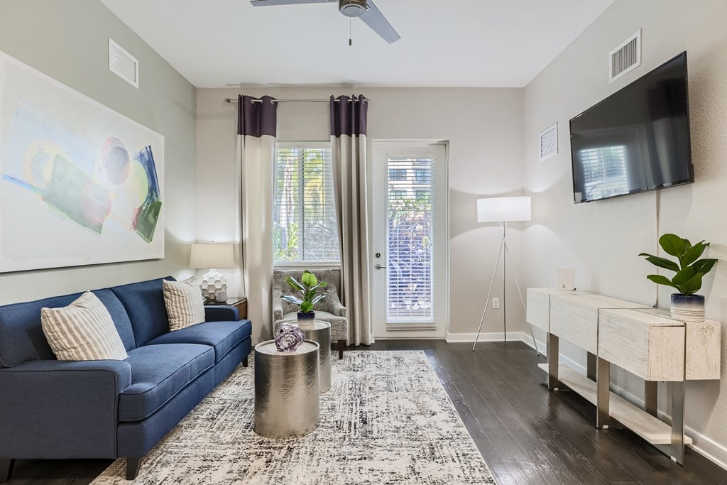 a living room with a blue couch and a tv on the wall