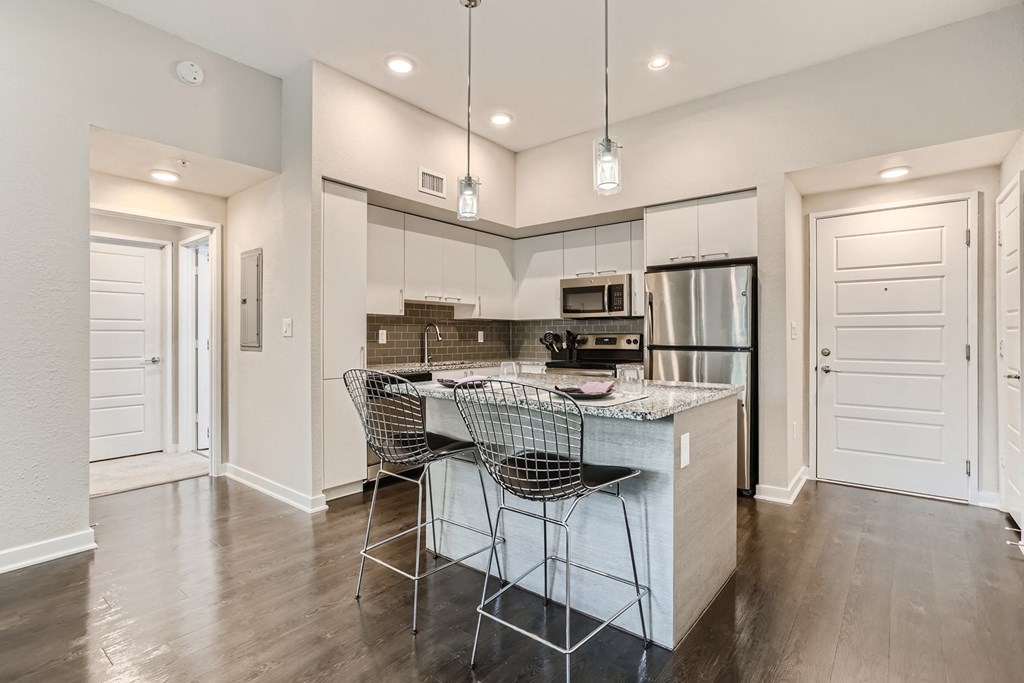 a kitchen with white cabinetry and a large island with a marble countertop