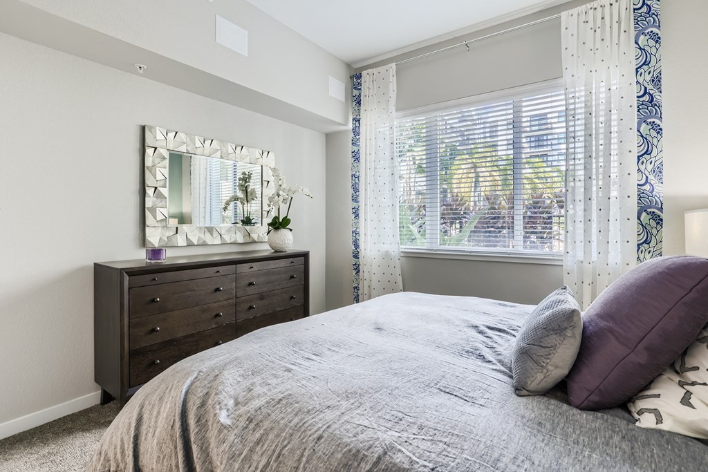 a bedroom with a large bed and a dresser with a mirror