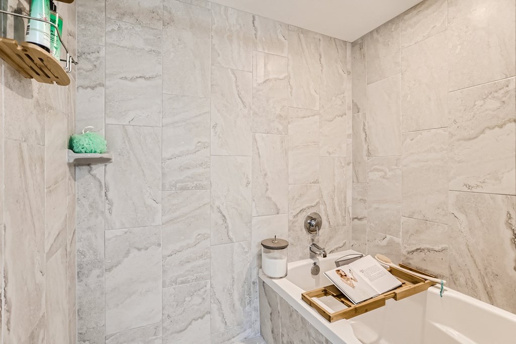 a bathroom with a white bathtub and a white sink with a wooden tray on top of