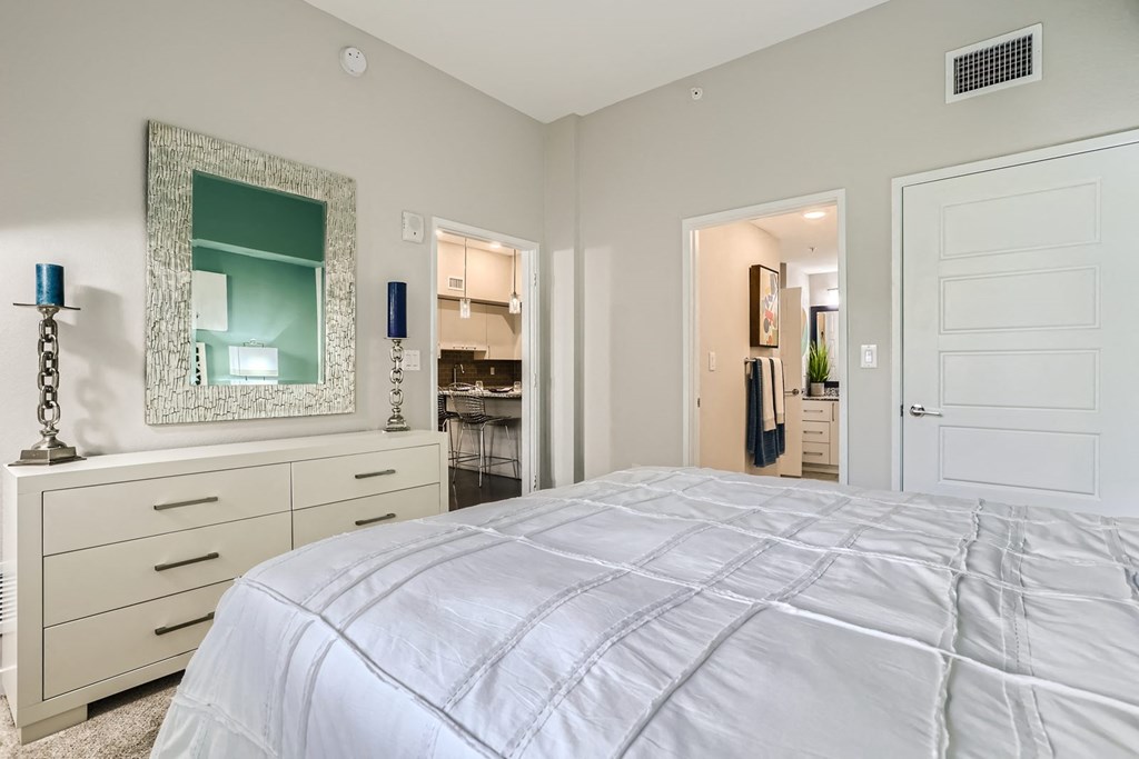 a bedroom with a white bed and a white dresser with a blue lamp