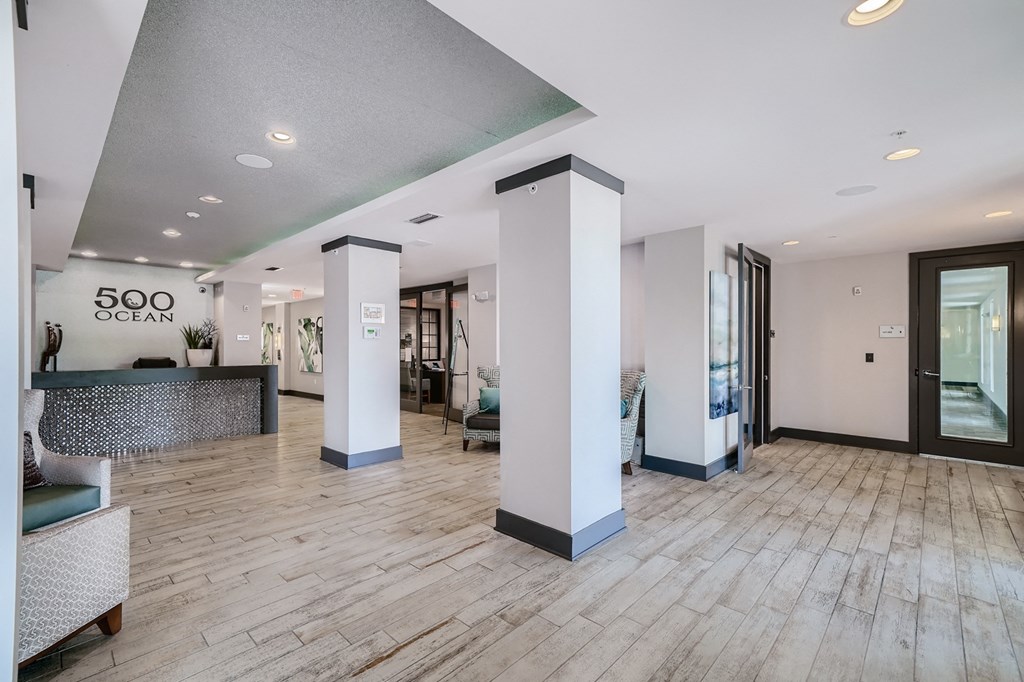 a lobby with white pillars and a wood floor and a glass door