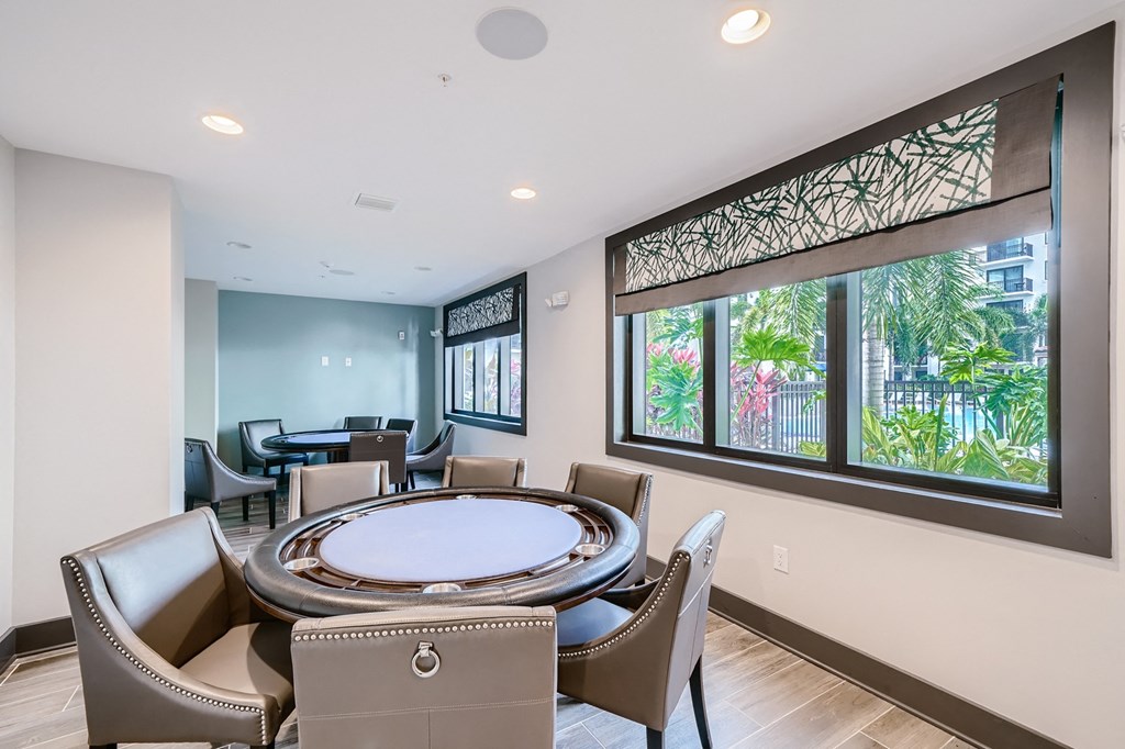 a round table with chairs in a room with large windows