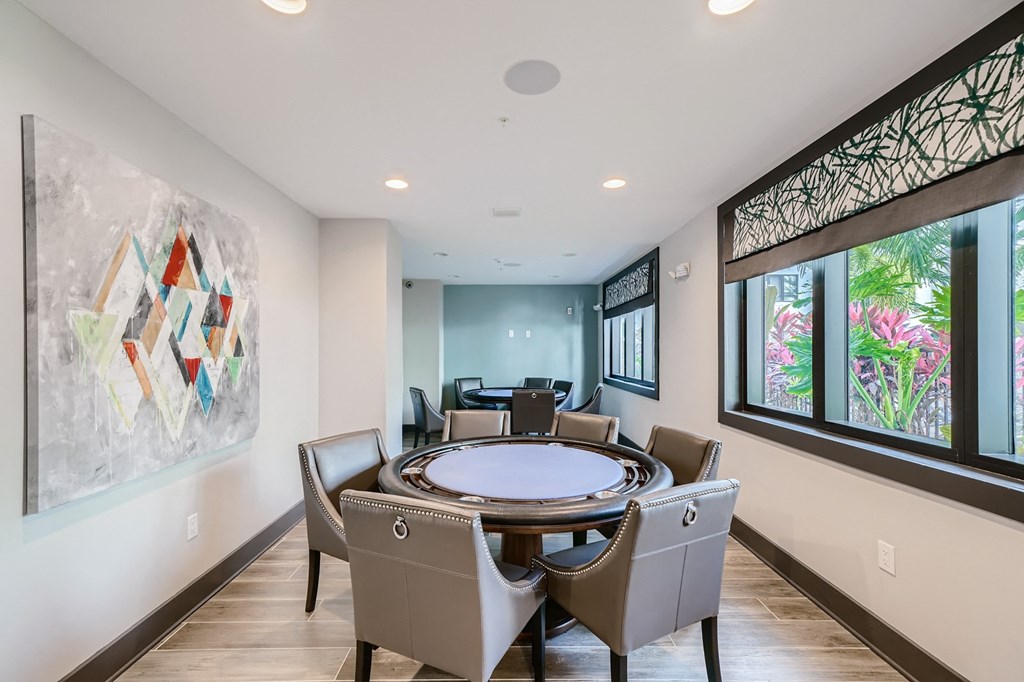 a round table with chairs in a room with large windows