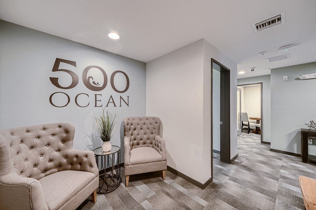a living room with two chairs and a logo on the wall