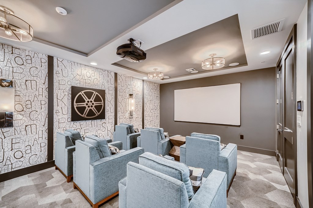 a theater room with blue chairs and a projector screen