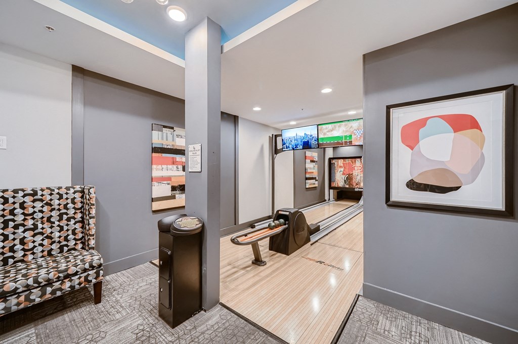 a bowling alley in the lobby of a building with a couch and a chair