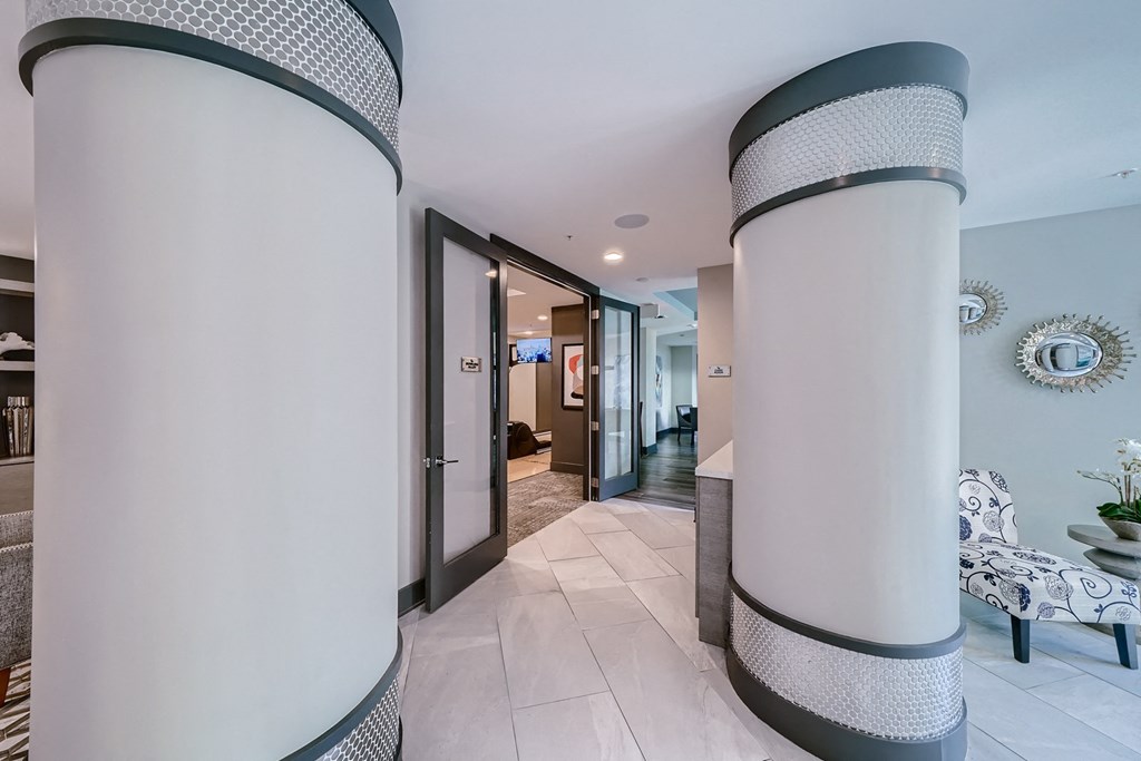 a hallway with white pillars and blue walls and a long hallway with doors and furniture