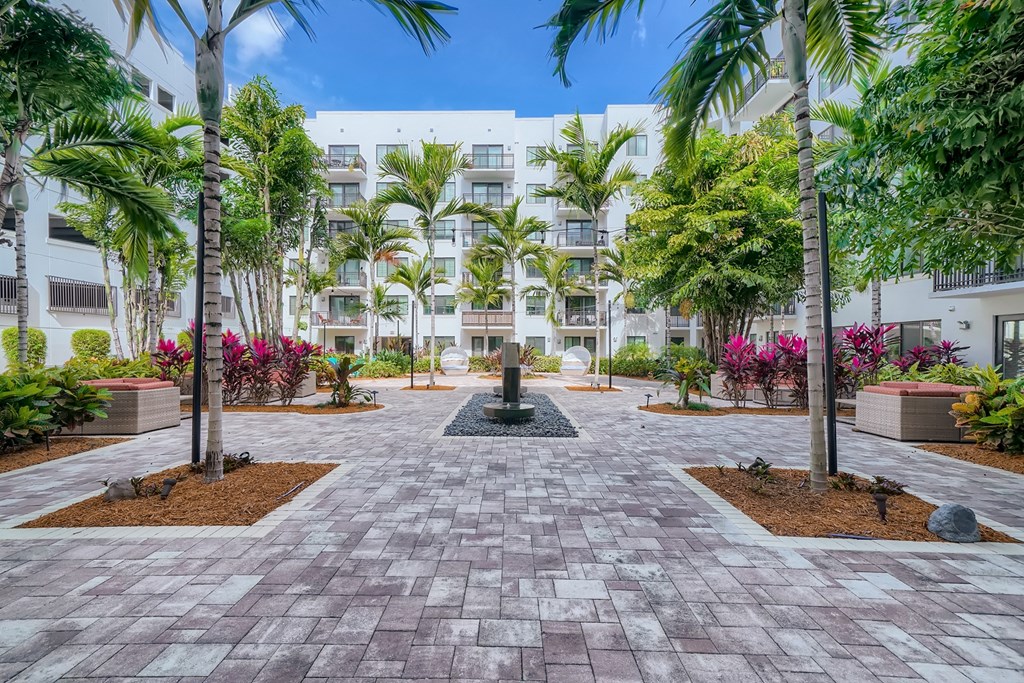 a courtyard with palm trees and a fountain in front of an apartment building