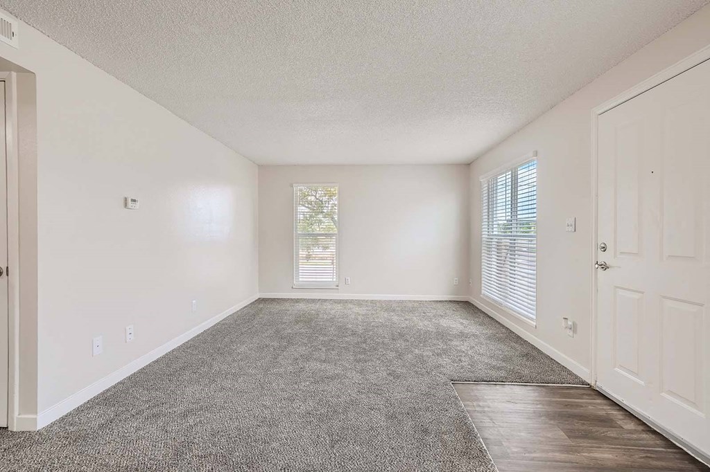 an empty living room with a door and window