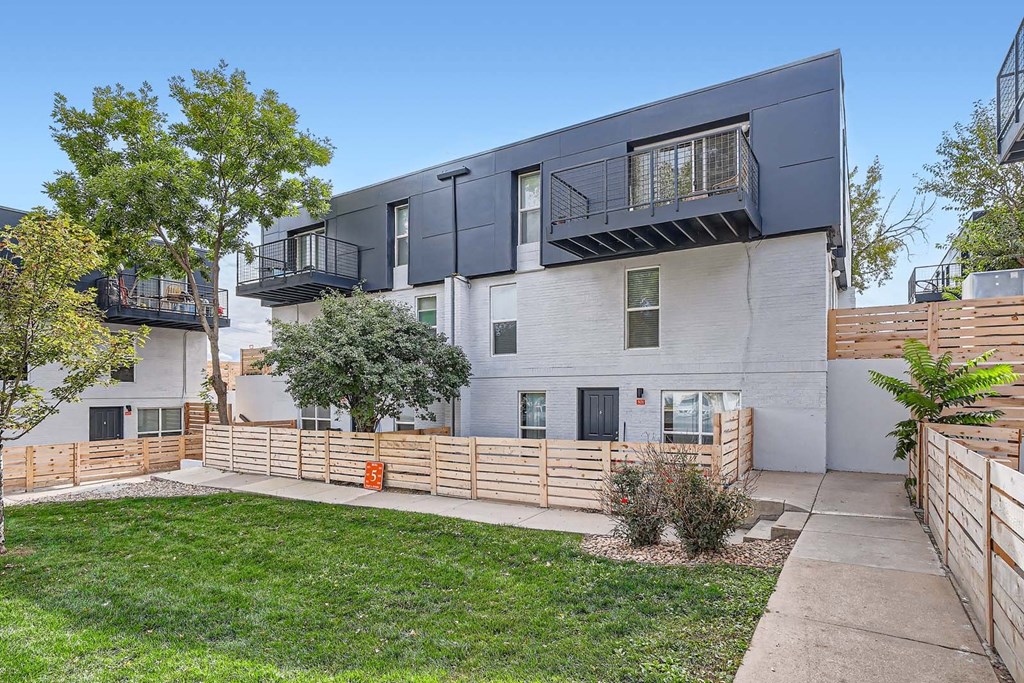 the exterior of an apartment building with a yard and a sidewalk