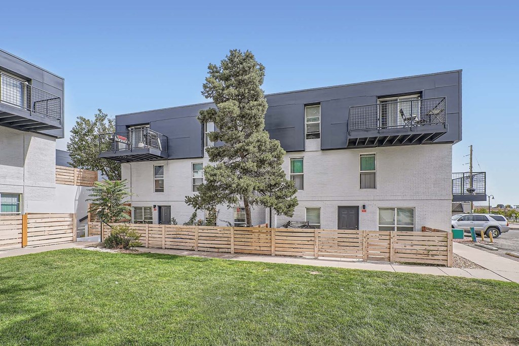 a view of an apartment building with a yard and a fence