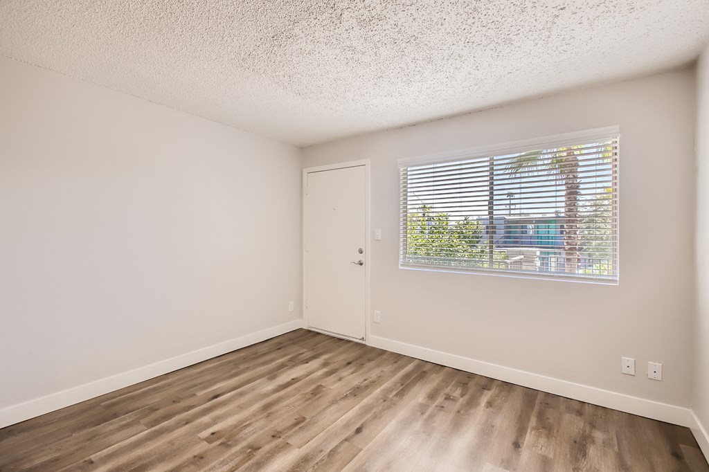 a bedroom with hardwood floors and a large window