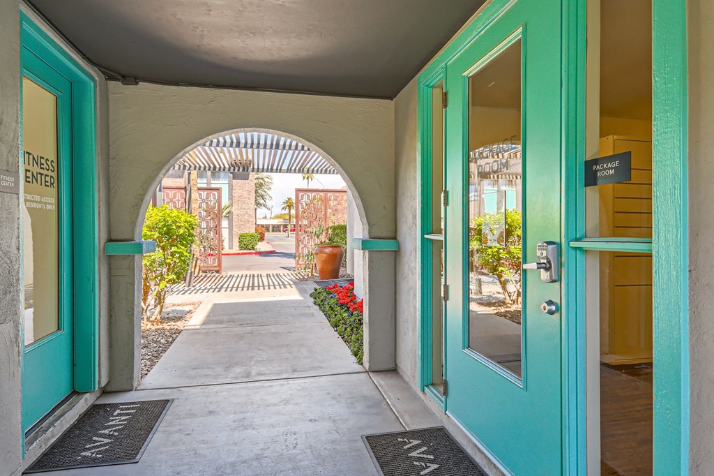 an open door with turquoise doors leading to a courtyard