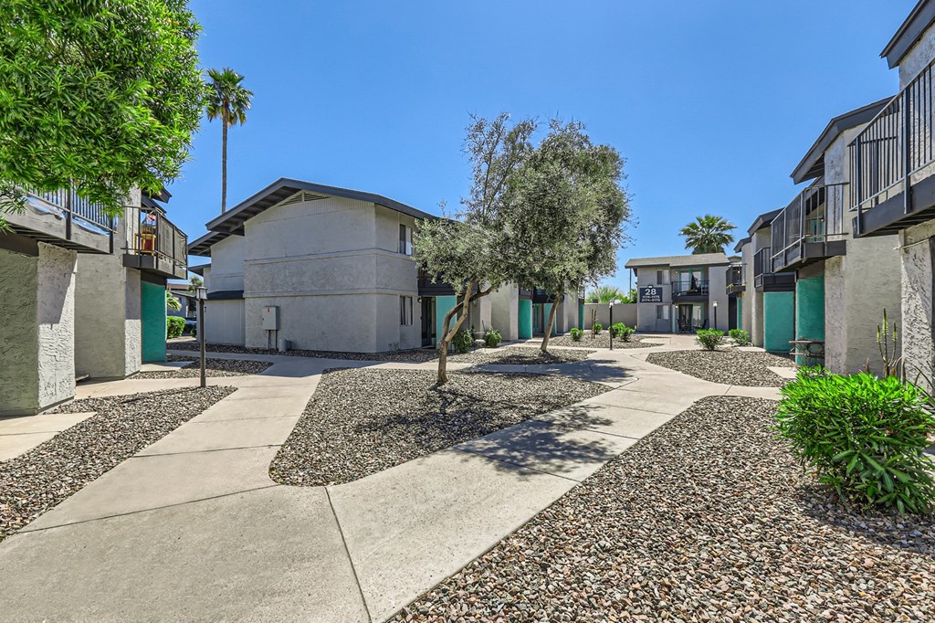 a courtyard between two buildings with trees and a blue sky