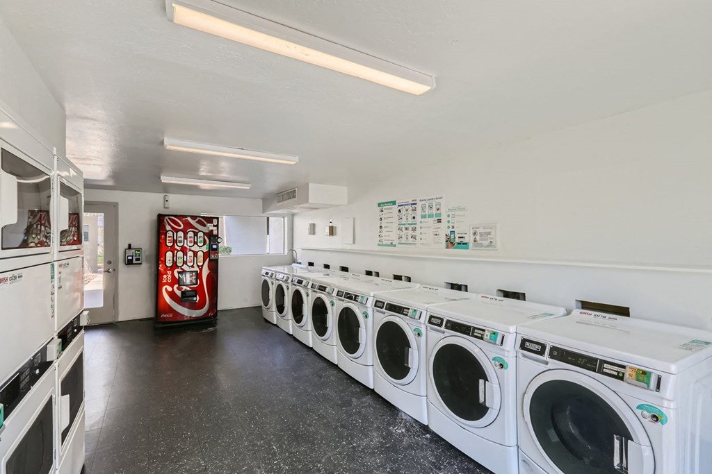 a row of washers and dryers in a laundry room with a red soda