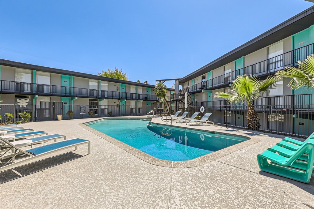 a swimming pool with lounge chairs in front of a building