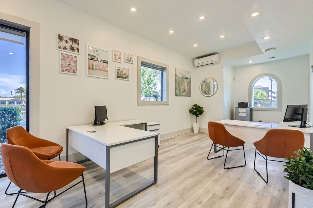 a white office with orange chairs and a white desk