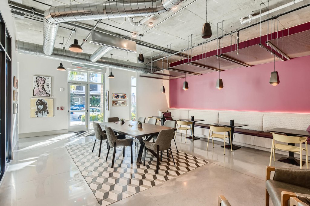 a dining room with tables and chairs and a pink wall