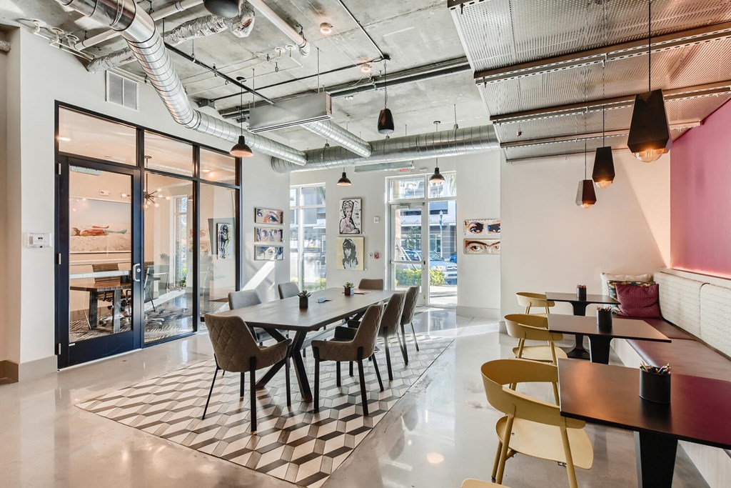 a dining area with a long table and chairs in a room with glass doors