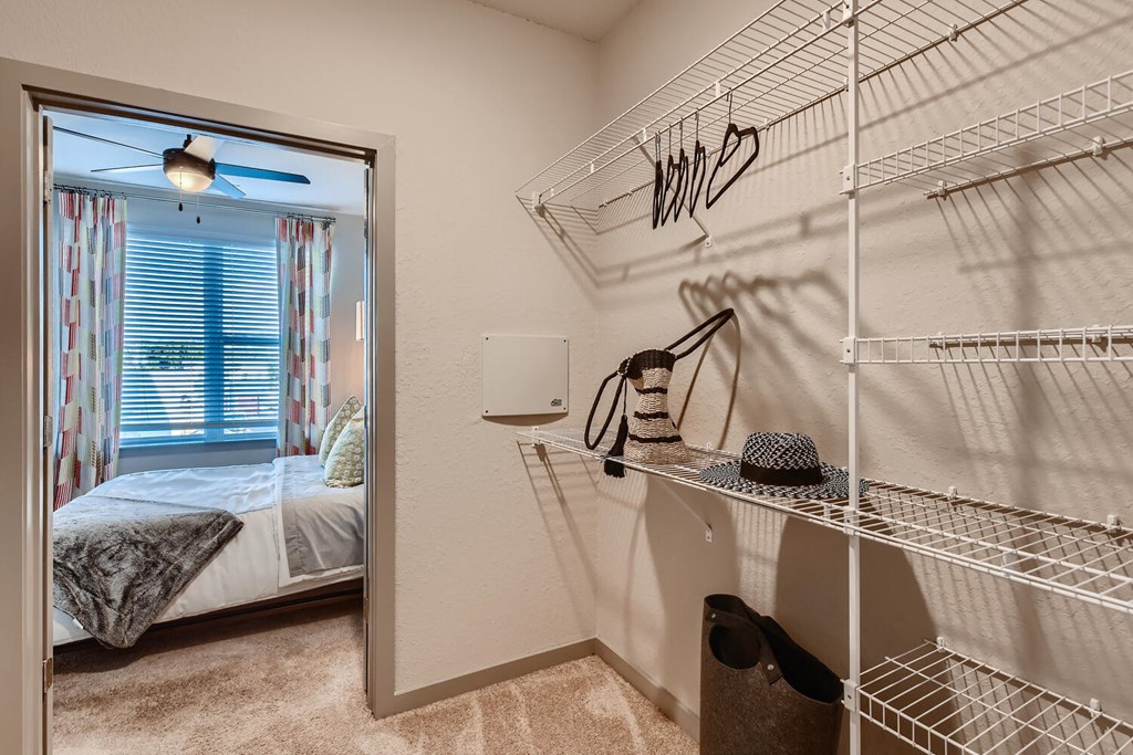 a closet in a bedroom with a bed and a mirror