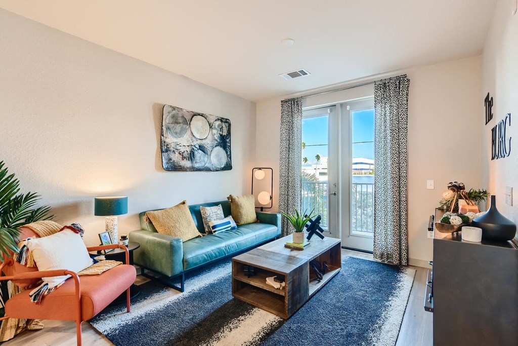 a living room with a large window and a blue rug