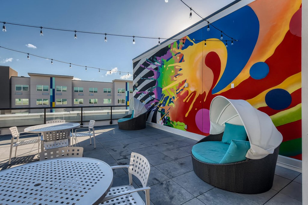 a patio with tables and chairs and a mural