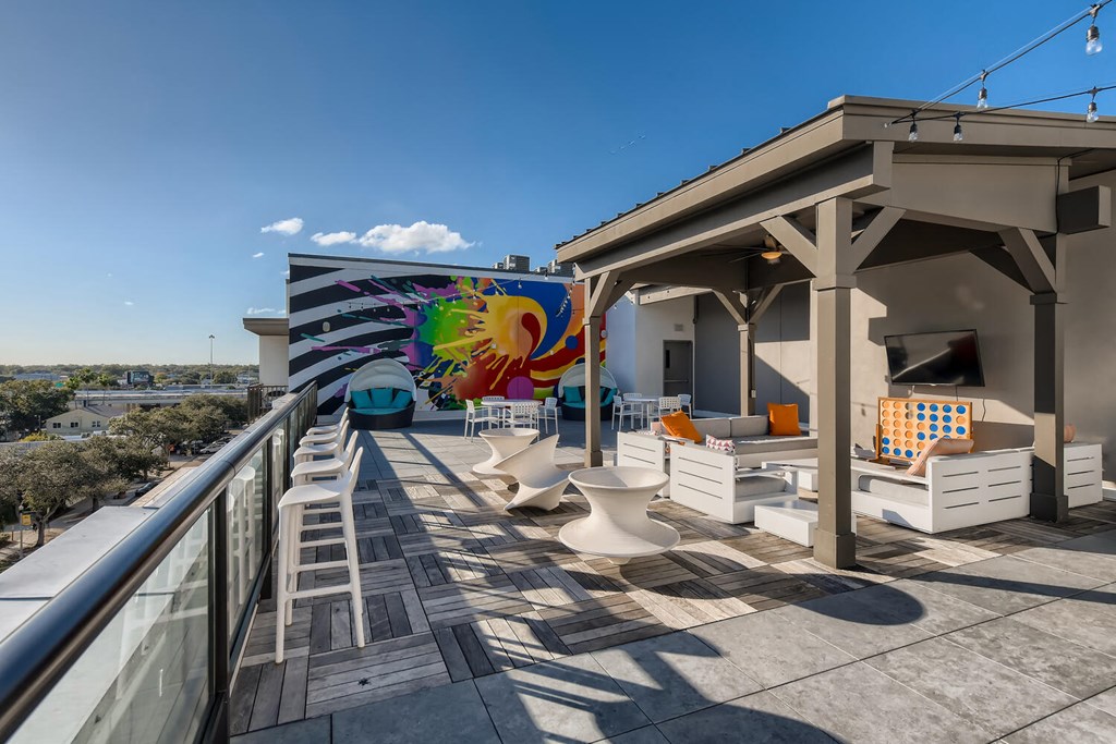 a rooftop deck with furniture and a mural on the side of a building