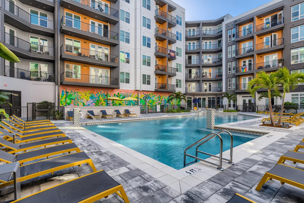 a swimming pool at an apartment building with yellow lounge chairs
