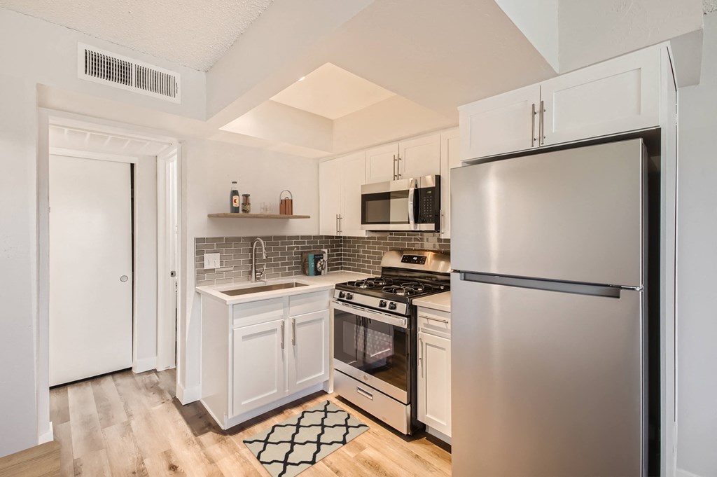 a kitchen with white cabinets and stainless steel appliances