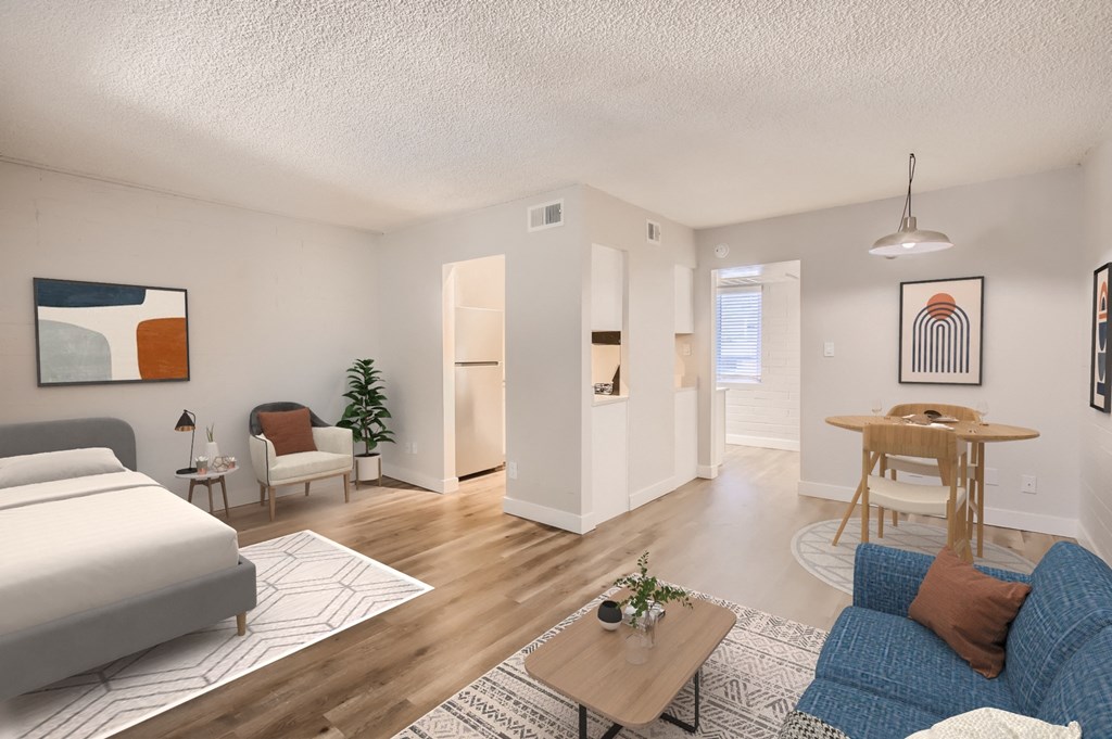 a bedroom and living room with hardwood floors and white walls