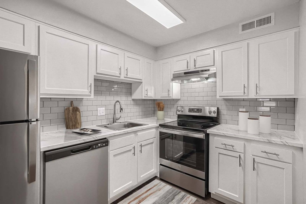 a white kitchen with stainless steel appliances and white cabinets