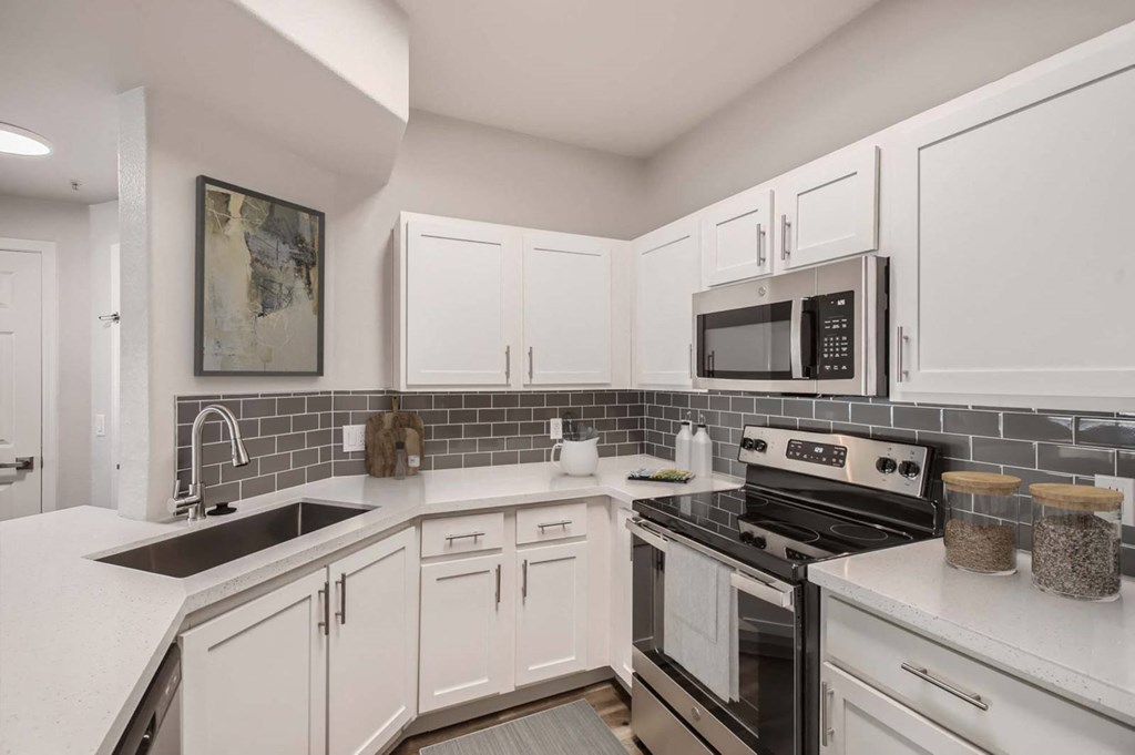 a kitchen with white cabinets and black appliances