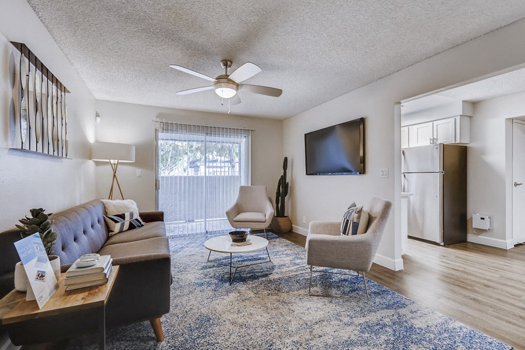 a living room with a couch and chairs and a ceiling fan