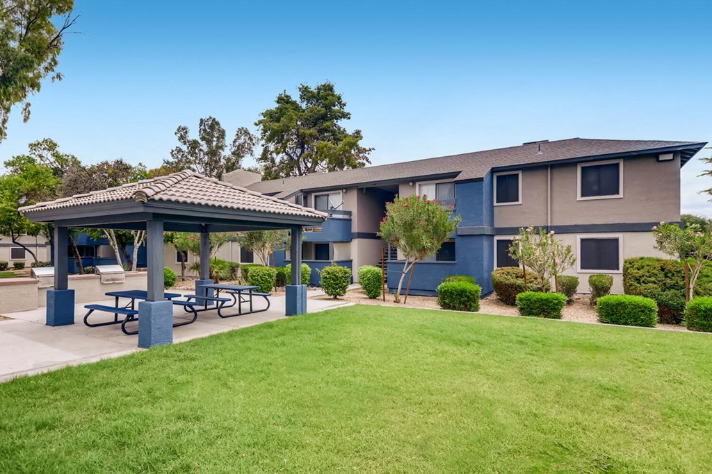 a patio with picnic tables in front of an apartment building