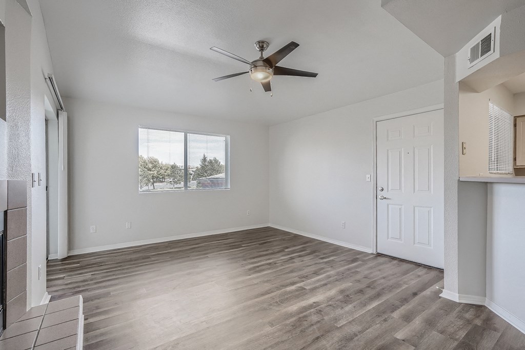 an empty living room with a ceiling fan and a window