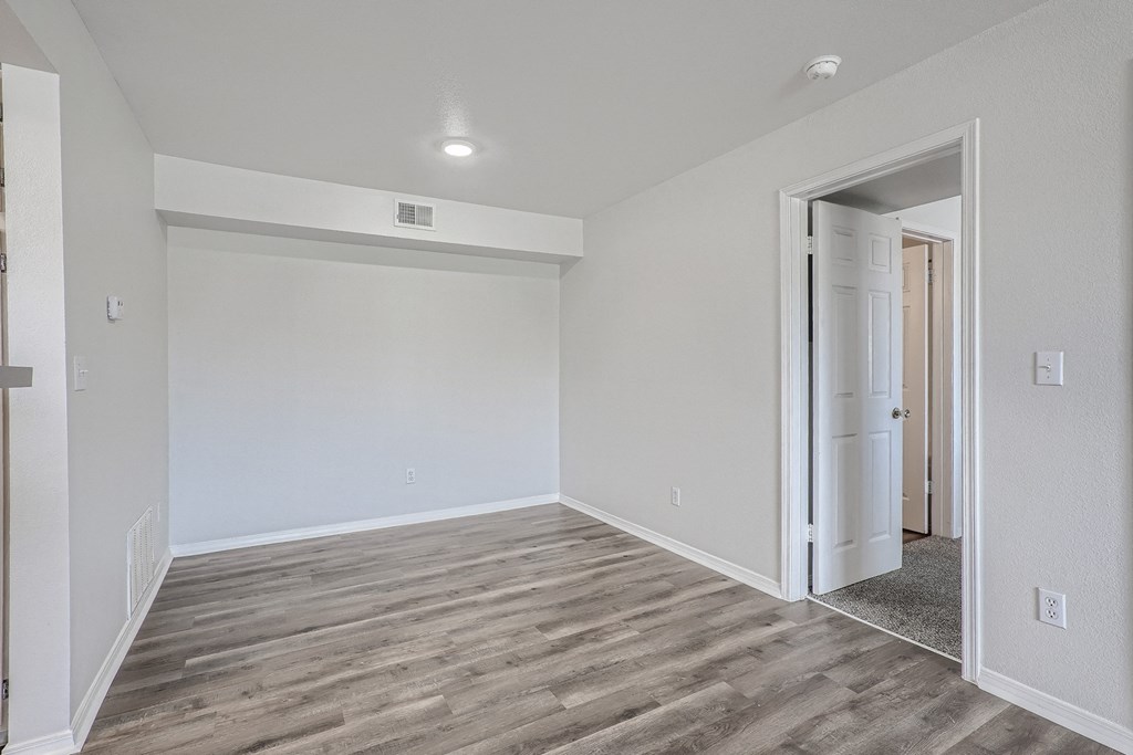 an empty bedroom with white walls and wood flooring